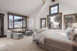 Experience breathtaking mountain views from this luxurious bedroom, featuring expansive windows that showcase a serene winter landscape.