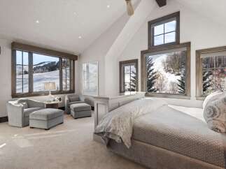 Experience breathtaking mountain views from this luxurious bedroom, featuring expansive windows that showcase a serene winter landscape.