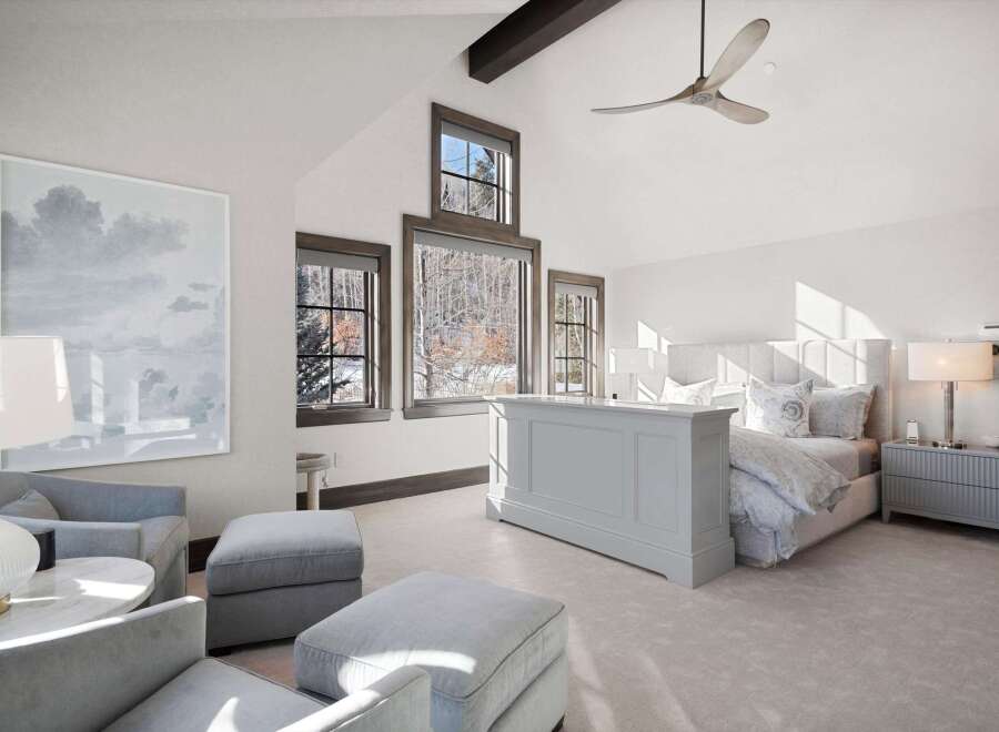 Experience luxury mountain living in this stunning bedroom featuring a vaulted ceiling with a modern fan and exposed beams.