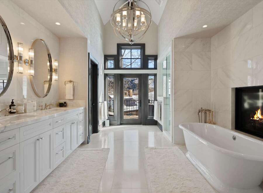 Indulge in luxury in this stunning master bathroom, featuring a freestanding soaking tub and a cozy fireplace for ultimate relaxation.