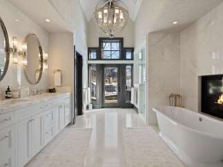 Indulge in luxury in this stunning master bathroom, featuring a freestanding soaking tub and a cozy fireplace for ultimate relaxation.