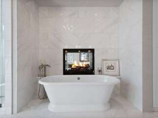 Indulge in ultimate relaxation in this luxurious bathroom featuring a freestanding soaking tub positioned before a cozy fireplace.