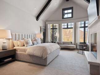 Experience luxury in this stunning master bedroom, featuring a plush king-sized bed with a tufted headboard and elegant decorative pillows.