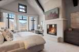 Experience luxury mountain living in this stunning bedroom featuring a cozy fireplace and breathtaking panoramic views.