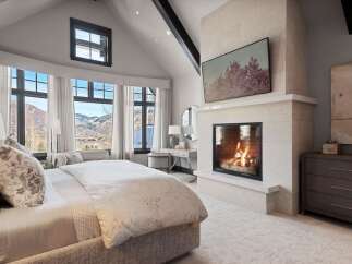 Experience luxury mountain living in this stunning bedroom featuring a cozy fireplace and breathtaking panoramic views.