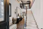 Step into this grand foyer featuring a striking staircase with plush carpeting and a dark wood banister.
