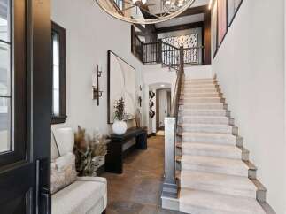 Step into this grand foyer featuring a striking staircase with plush carpeting and a dark wood banister.