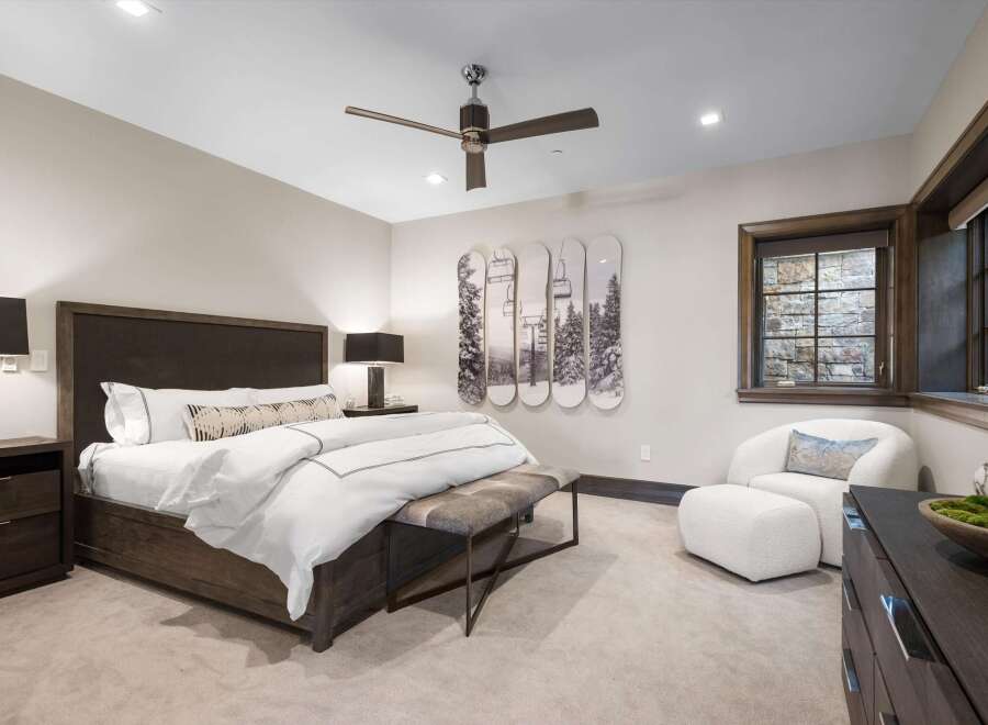 Experience luxury mountain living in this stunning bedroom, featuring a king-sized bed with crisp white linens and a stylish upholstered headboard.