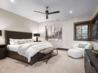 Experience luxury mountain living in this stunning bedroom, featuring a king-sized bed with crisp white linens and a stylish upholstered headboard.