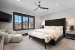 Experience luxury mountain living in this stunning bedroom, featuring a plush tufted headboard and a cozy seating area with a view.