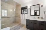 Experience luxury in this modern bathroom featuring a spacious walk-in shower with elegant tilework and a sleek vanity with ample storage.