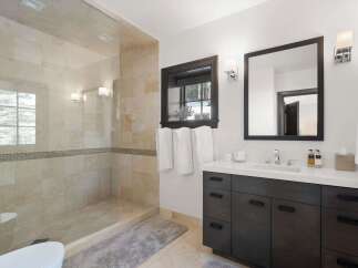 Experience luxury in this modern bathroom featuring a spacious walk-in shower with elegant tilework and a sleek vanity with ample storage.