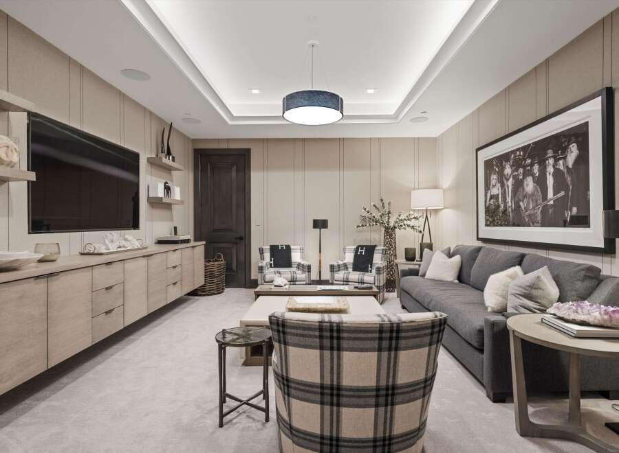 Experience luxury living in this sophisticated media room, featuring a large wall-mounted television and a sleek, modern entertainment console.