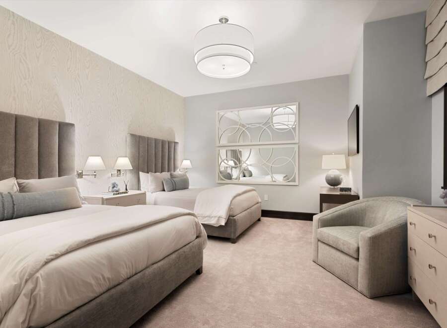 Experience luxurious comfort in this elegantly appointed bedroom featuring two plush queen beds with sophisticated upholstered headboards.