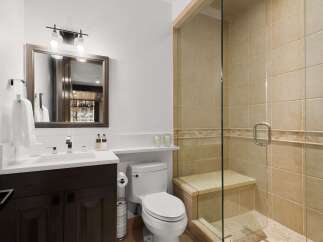 This modern bathroom features a sleek vanity with a white countertop and dark wood cabinetry, complemented by a stylish chrome faucet.