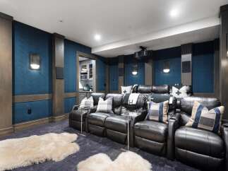 Experience cinematic bliss in this luxurious home theater, featuring plush leather recliners and a state-of-the-art projector.