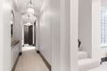 Step into this elegant hallway featuring a plush carpet and sophisticated pendant lighting that guides you towards dark wood doors.