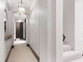 Step into this elegant hallway featuring a plush carpet and sophisticated pendant lighting that guides you towards dark wood doors.