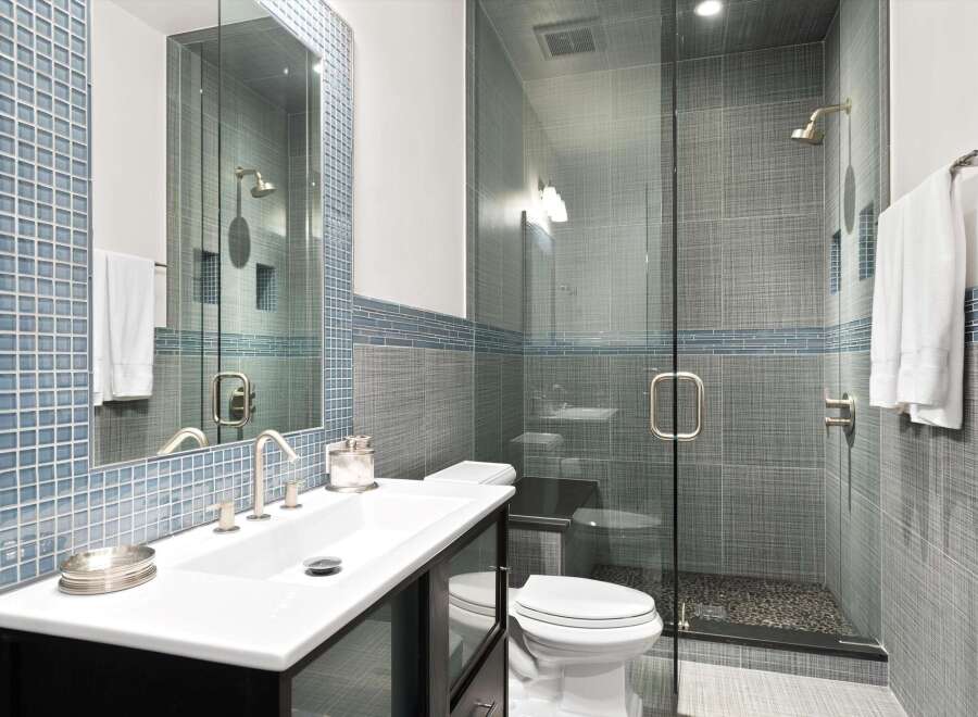 Experience modern luxury in this stunning bathroom, featuring a sleek vanity with a vessel sink and a spacious glass-enclosed shower with a rainfall showerhead.