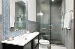 Experience modern luxury in this stunning bathroom, featuring a sleek vanity with a vessel sink and a spacious glass-enclosed shower with a rainfall showerhead.