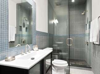 Experience modern luxury in this stunning bathroom, featuring a sleek vanity with a vessel sink and a spacious glass-enclosed shower with a rainfall showerhead.