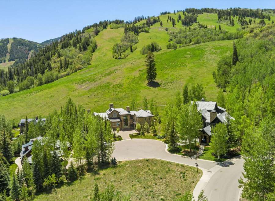Experience luxury mountain living in this stunning estate, nestled against a backdrop of lush green ski slopes and mature trees.