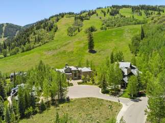 Experience luxury mountain living in this stunning estate, nestled against a backdrop of lush green ski slopes and mature trees.
