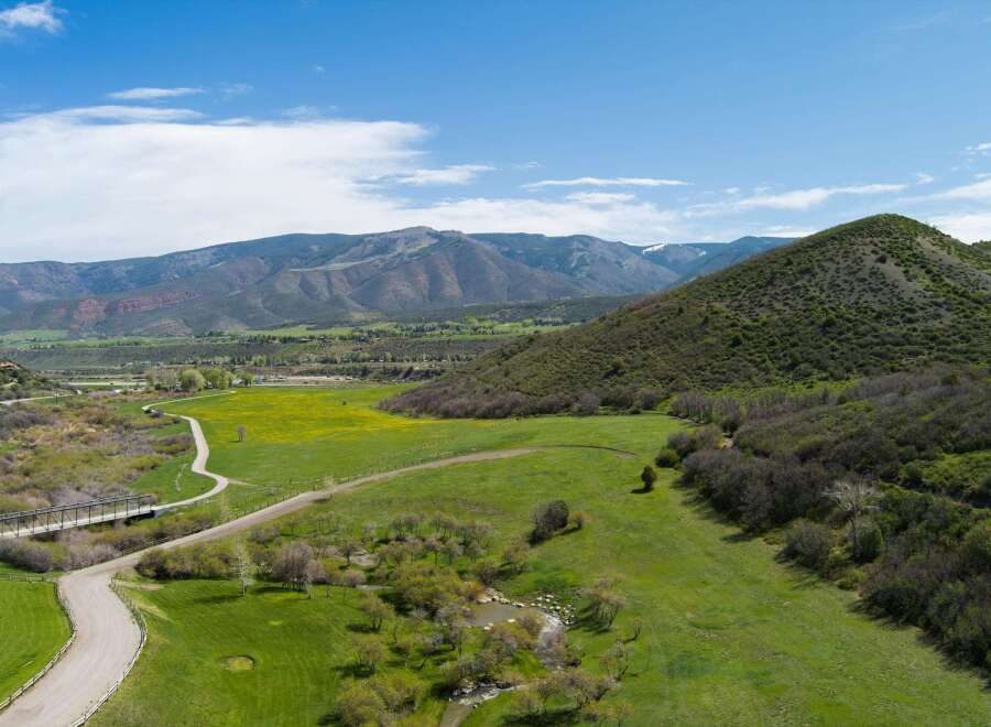 Discover this stunning property featuring rolling green hills, a vibrant yellow wildflower meadow, and a serene creek.