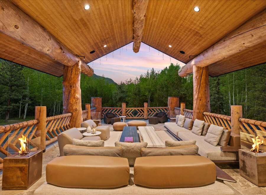 Experience luxurious outdoor living in this stunning mountain retreat, featuring a spacious covered patio with a cozy seating area and modern fire pits.