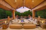 Experience luxurious outdoor living in this stunning mountain retreat, featuring a spacious covered patio with a cozy seating area and modern fire pits.