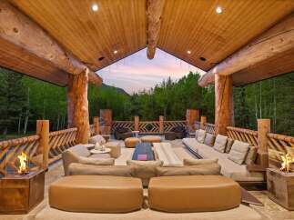 Experience luxurious outdoor living in this stunning mountain retreat, featuring a spacious covered patio with a cozy seating area and modern fire pits.