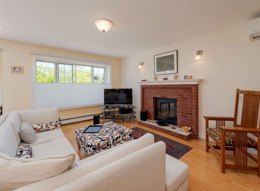 Step into this inviting living room, featuring a cozy brick fireplace and a large sectional sofa perfect for relaxation.