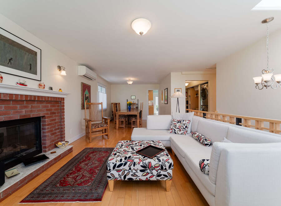 Experience comfortable living in this inviting space, featuring a cozy brick fireplace and a spacious sectional sofa adorned with decorative pillows.