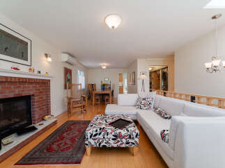 Experience comfortable living in this inviting space, featuring a cozy brick fireplace and a spacious sectional sofa adorned with decorative pillows.