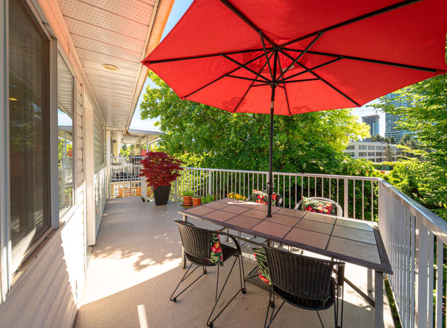 Enjoy outdoor living on this spacious balcony, perfect for al fresco dining or relaxing under the vibrant red umbrella.
