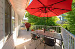 Enjoy outdoor living on this spacious balcony, perfect for al fresco dining or relaxing under the vibrant red umbrella.