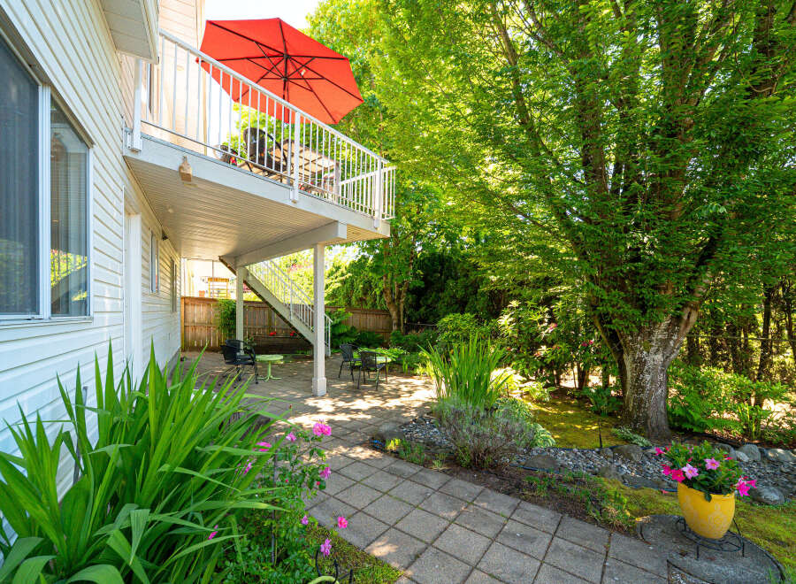 Enjoy outdoor living with this charming backyard featuring a spacious deck perfect for entertaining and a lower patio area ideal for relaxing.