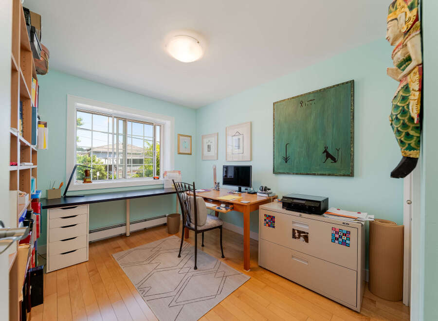 This home office features a large window with a view of the outdoors, providing ample natural light.
