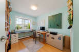 This home office features a large window with a view of the outdoors, providing ample natural light.