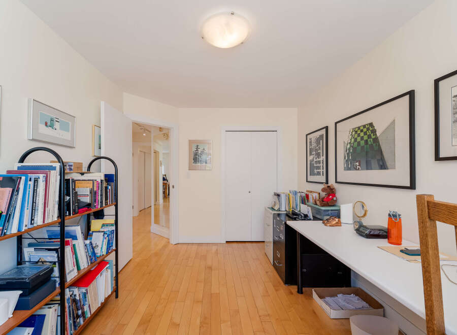This home office features a spacious white desk with a wooden chair, perfect for productive work sessions.
