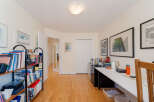 This home office features a spacious white desk with a wooden chair, perfect for productive work sessions.