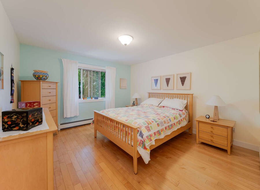 This charming bedroom features a cozy queen-size bed adorned with a colorful patchwork quilt, perfect for restful nights.