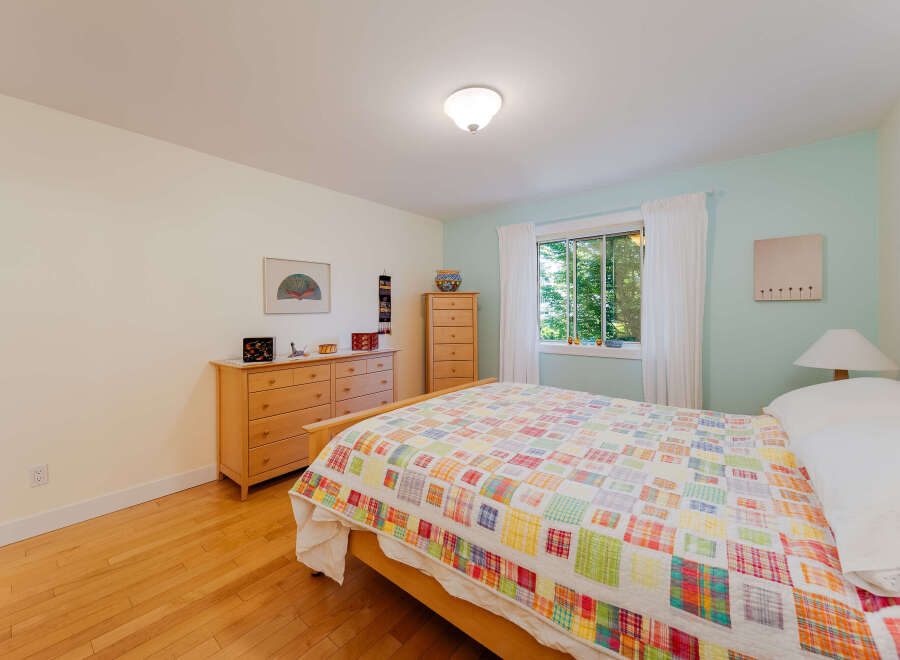 Bright and airy bedroom featuring a comfortable bed adorned with a colorful patchwork quilt.