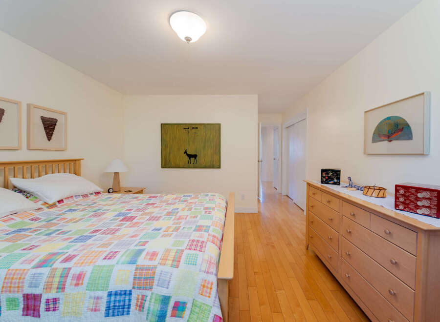 This charming bedroom features a comfortable queen-size bed adorned with a vibrant, patchwork quilt and crisp white linens.