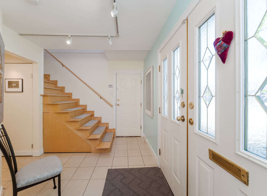 Step into a welcoming entryway featuring a stylish staircase with wooden treads and carpeted steps, perfect for a cozy home.