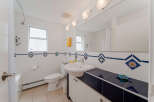 This bright and clean bathroom features a white tiled shower with a curved rod and a white shower curtain.