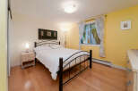 Bright and inviting bedroom featuring a comfortable queen-size bed with crisp white linens, complemented by a sleek black metal frame.