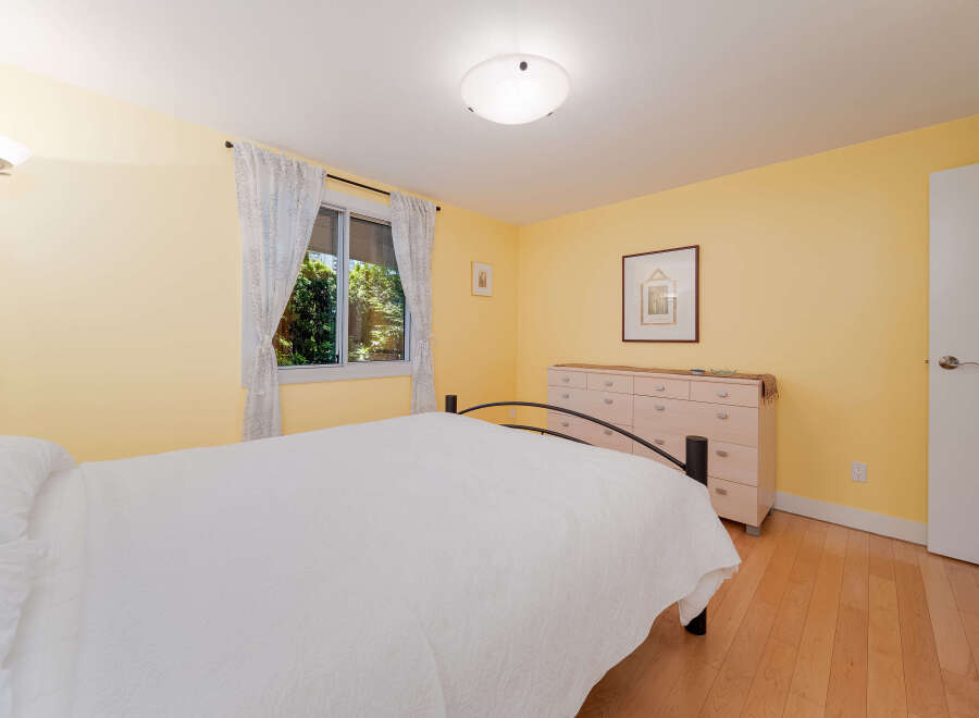 This charming bedroom features a comfortable queen-size bed with crisp white linens, perfect for a restful night's sleep.