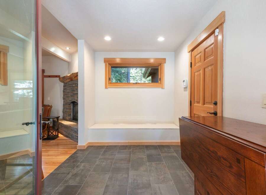 Step into this inviting entryway featuring a cozy stone fireplace and warm wood accents throughout.