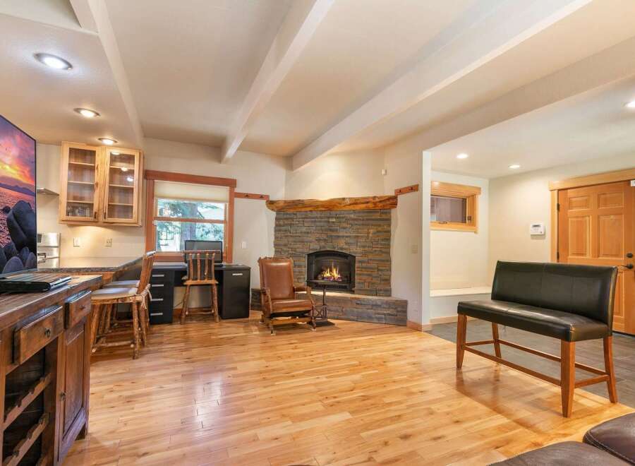 Cozy living room featuring a rustic stone fireplace with a natural wood mantel, perfect for gathering on cool evenings.